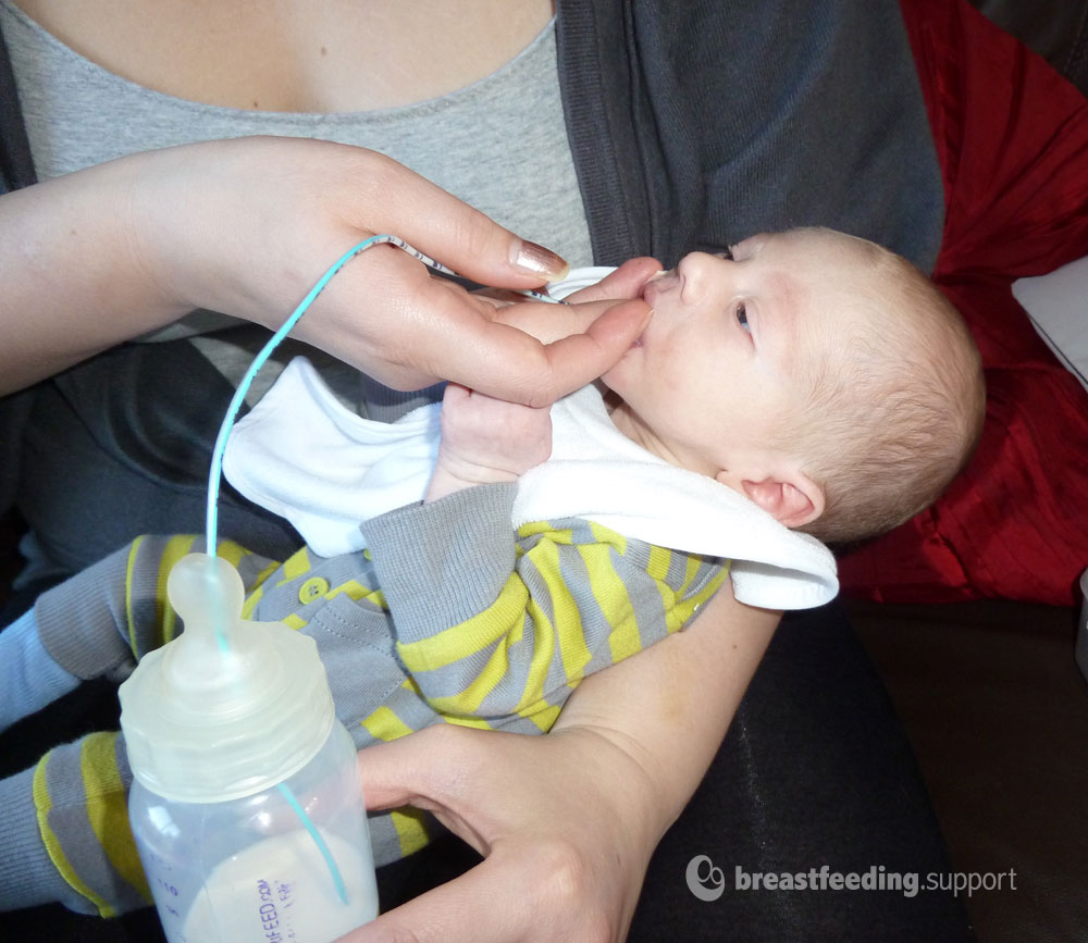 A baby finger feeding with a supplemental nursing system