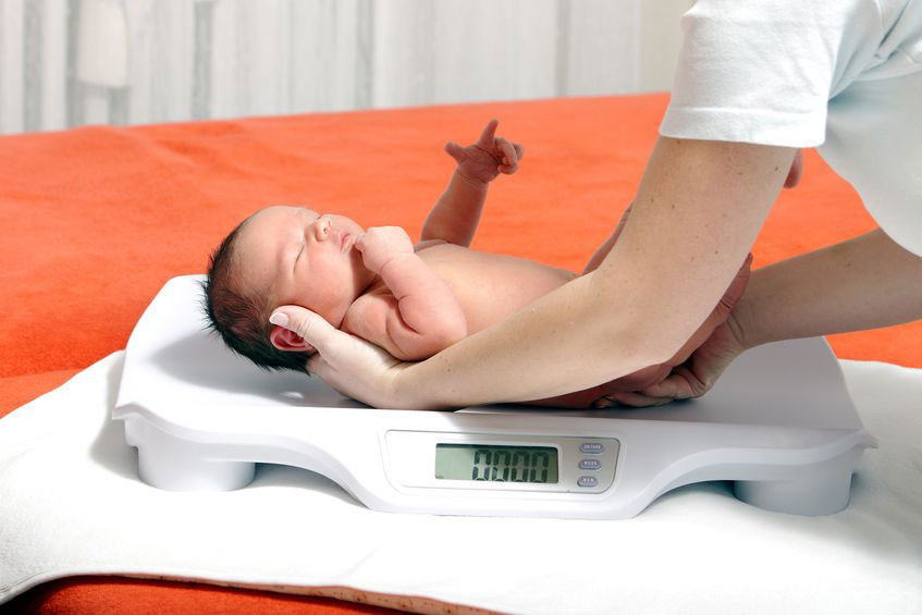 baby being lowered onto weighing scales