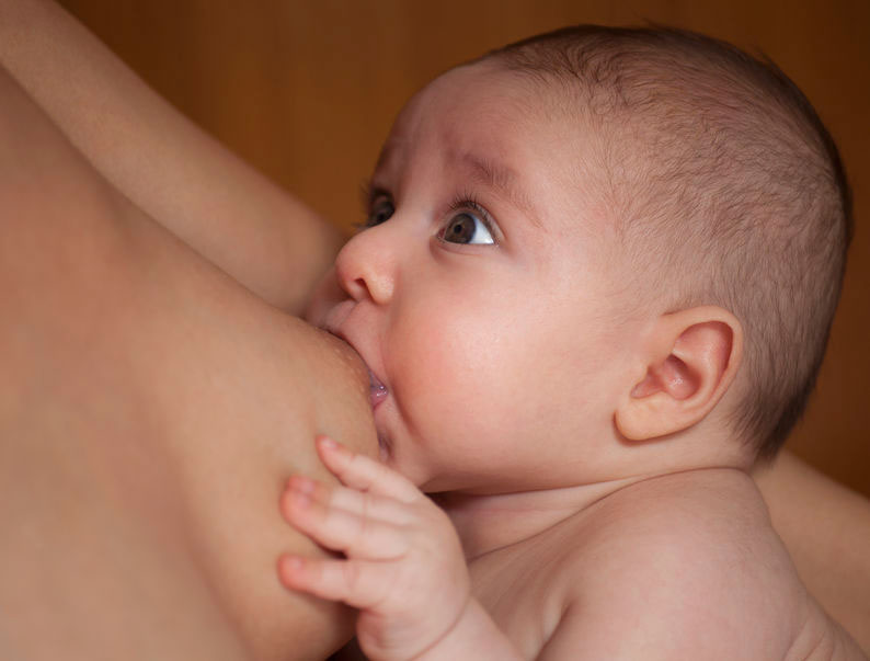 Baby breastfeeding and looking surprised