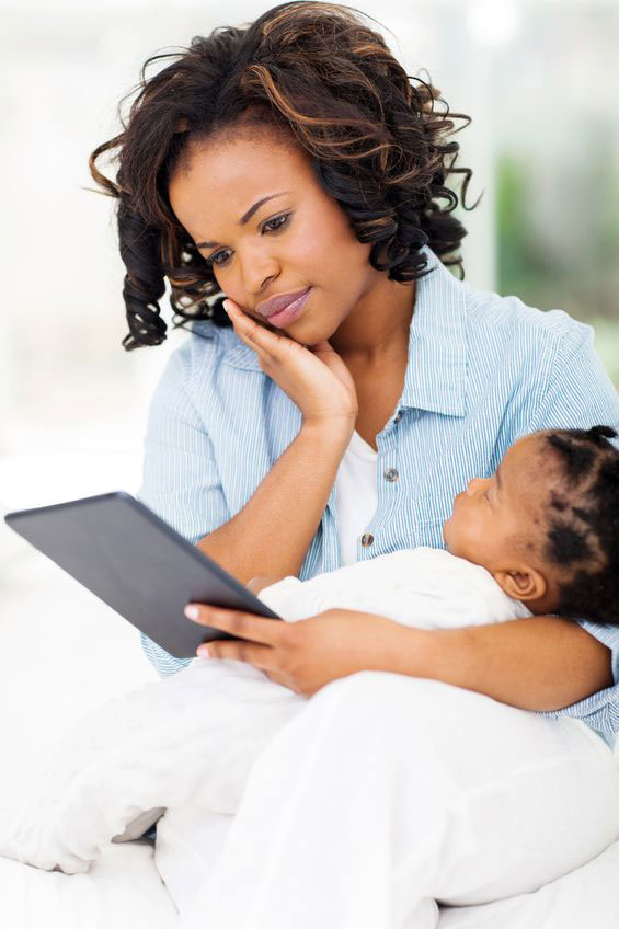 Mother looking at a tablet or iPad while holding her baby