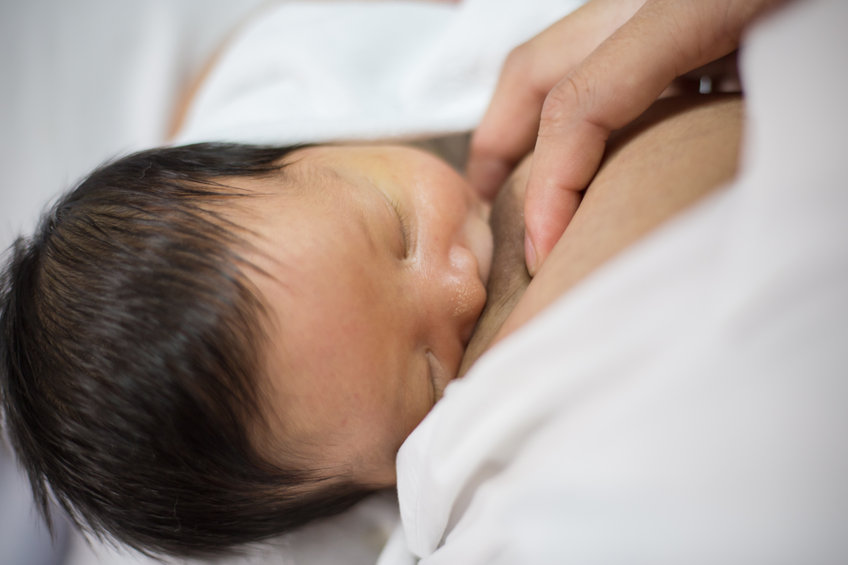 close up of dark haired baby breastfeeding