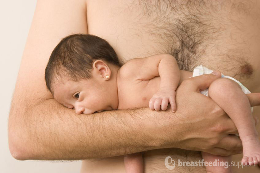 dad holds baby skin to skin in the colic hold