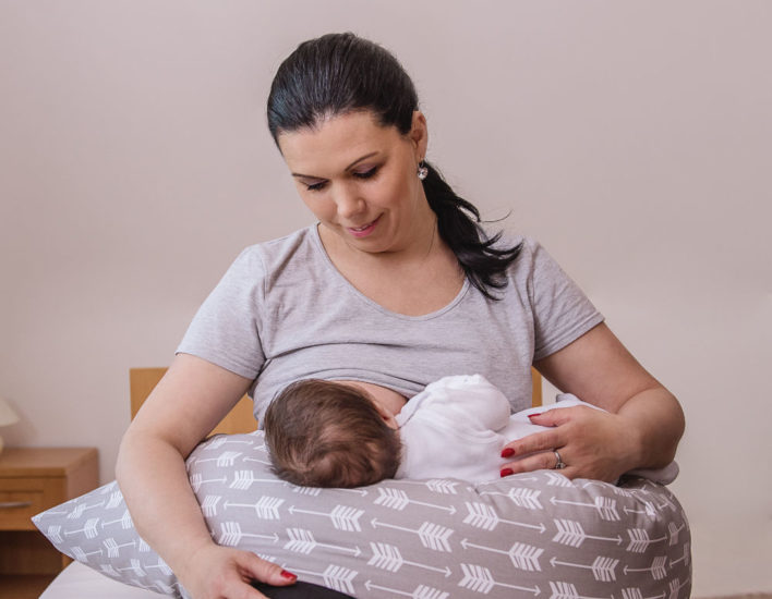 mother breastfeeding her baby on a big firm pillow