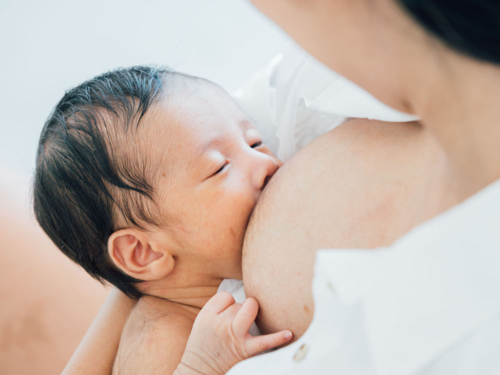 Baby with lots of dark hair falling asleep while breastfeeding