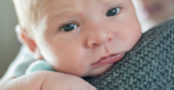 baby looking uncomfortable on mother's shoulder