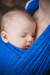 Baby carried in a sling snug on mother's chest