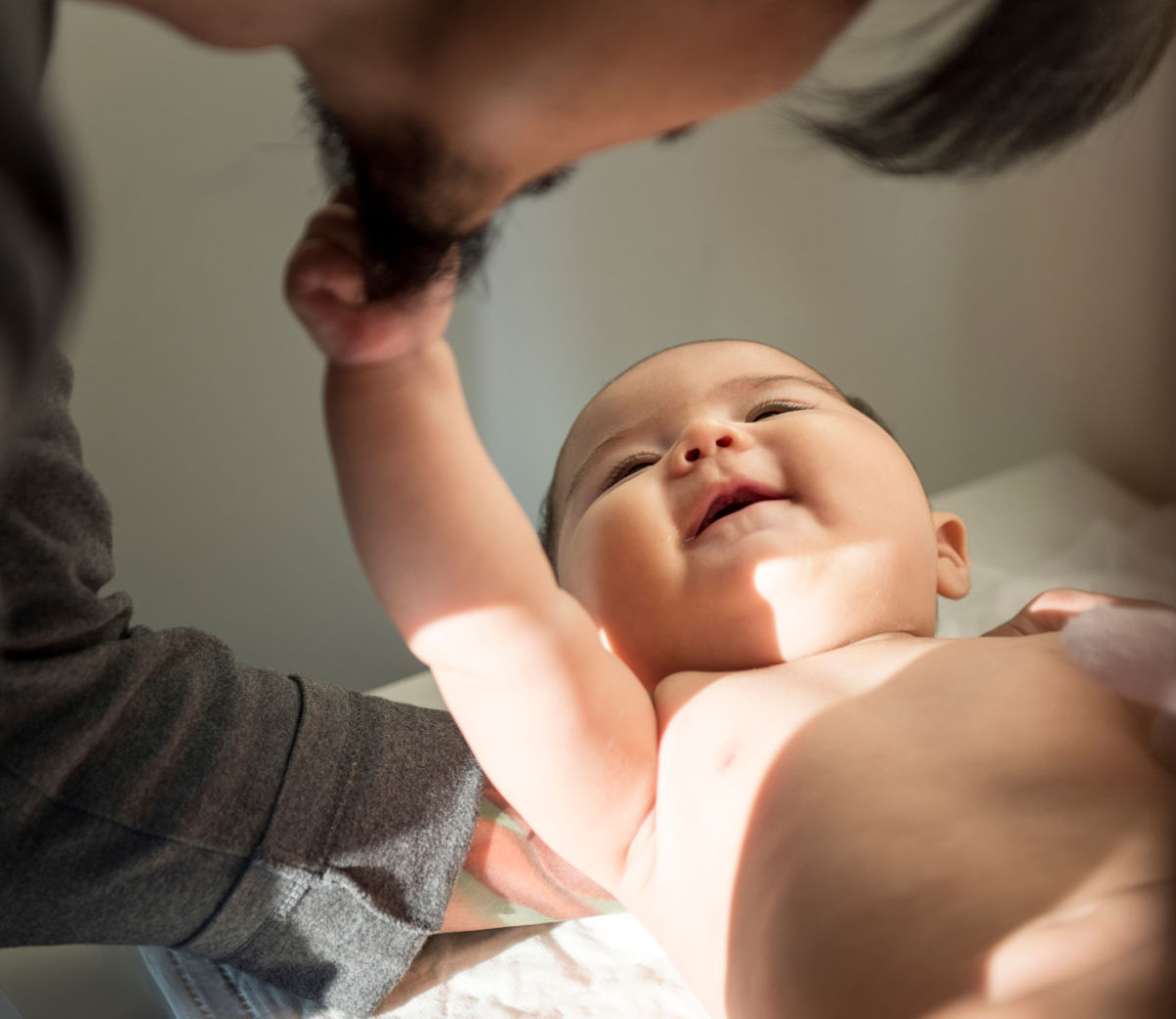 baby gazing up at dad and grasping his beard