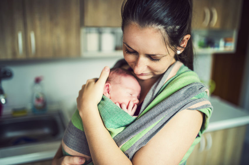 Little baby in a green wrap in kangaroo care