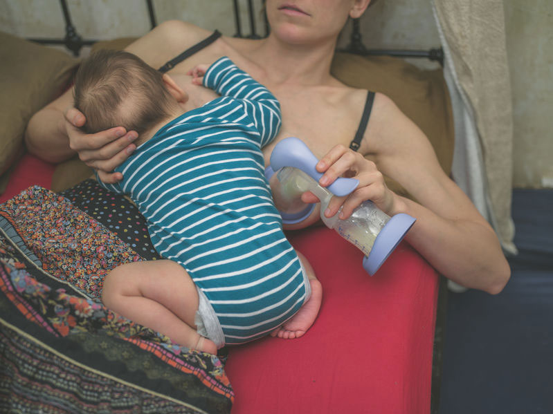 Mother breastfeeding on one breast and pumping on the other