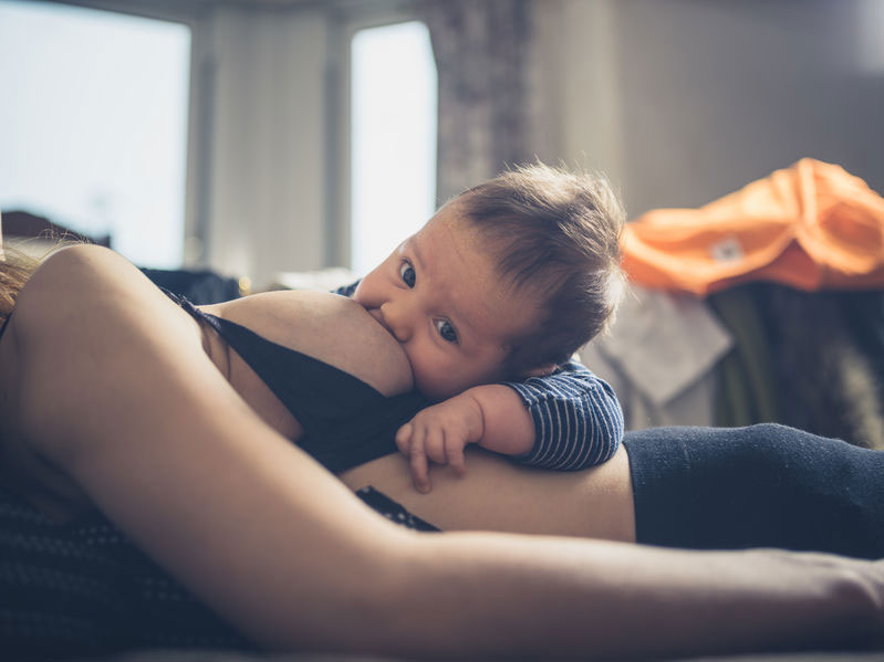 Mother reclining while baby breastfeeds
