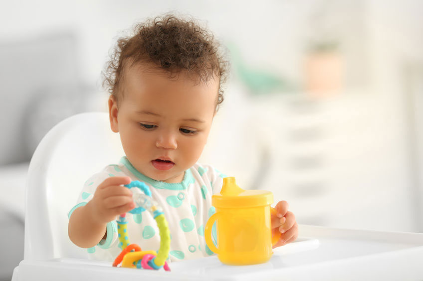 baby with a yellow sippy cup and toy