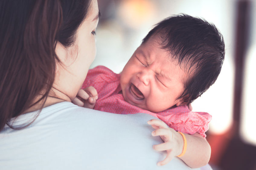 bébé pleurant tenu sur l'épaule de sa mère's shoulder